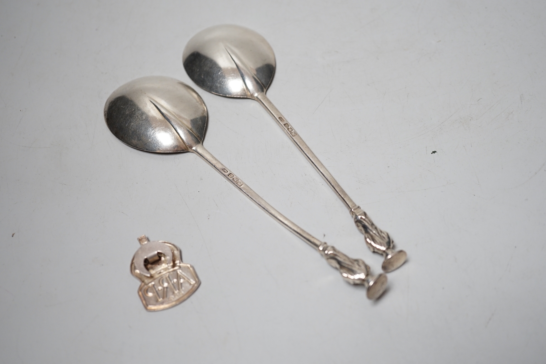 A pair of Edwardian silver apostle spoons, London, 1906 and an ARP badge